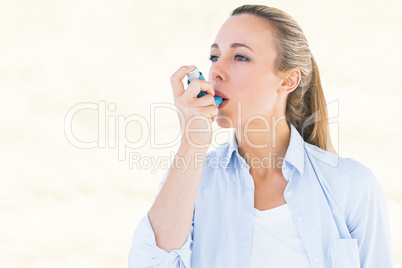 Composite image of pretty blonde using an asthma inhaler