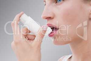 Composite image of blonde woman taking her inhaler