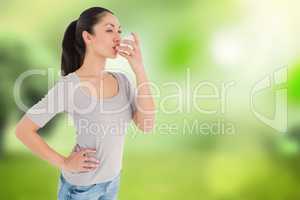 Composite image of asthmatic pretty brunette using inhaler