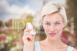 Composite image of pretty woman holding inhaler smiling at camera