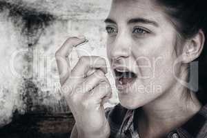 Composite image of woman having asthma using the asthma inhaler