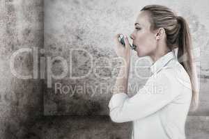 Composite image of beautiful blonde using an asthma inhaler