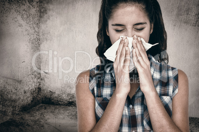 Composite image of beautiful woman sneezing in a tissue