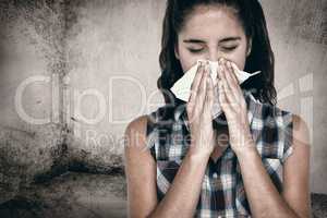 Composite image of beautiful woman sneezing in a tissue