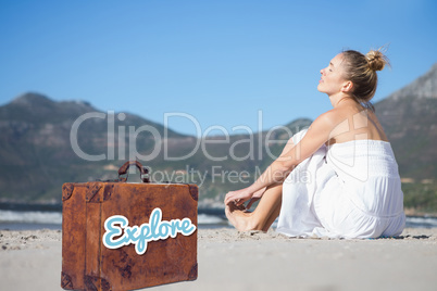 Composite image of content blonde in white dress sitting on the beach
