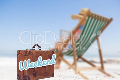 Composite image of woman in sunhat sitting on beach in deck chair using tablet pc