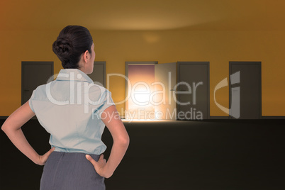 Composite image of rear view of businesswoman standing with hands on hips