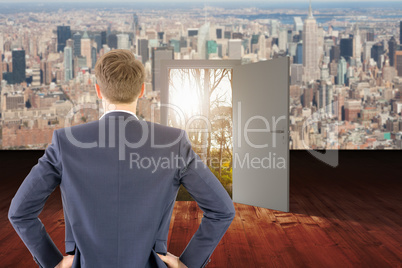 Composite image of rear view of businessman standing with hands on wiast