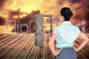 Composite image of rear view of businesswoman standing with hands on hips