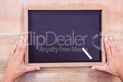 Composite image of hand holding a chalkboard