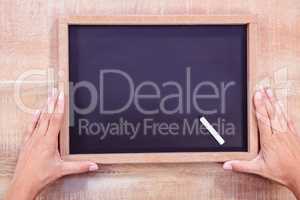 Composite image of hand holding a chalkboard
