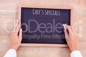 Composite image of chef hand writing on a chalkboard