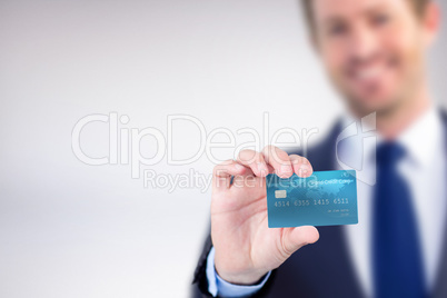 Composite image of happy businessman showing a creditcard