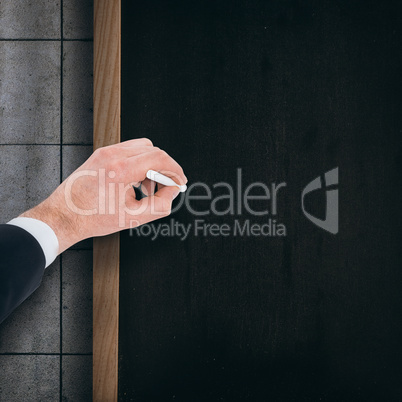 Composite image of hand of businessman writing with a white chalk