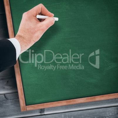 Composite image of hand of businessman writing with a white chalk