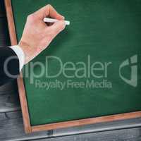 Composite image of hand of businessman writing with a white chalk