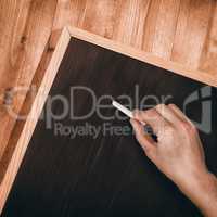 Composite image of hand writing with chalk