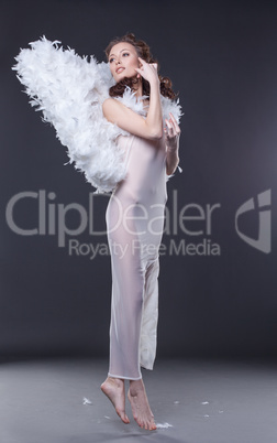 Charming woman in angel costume hovers above floor