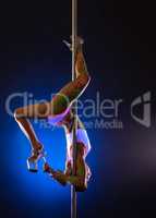 Flexible dancer hangs upside down on pole