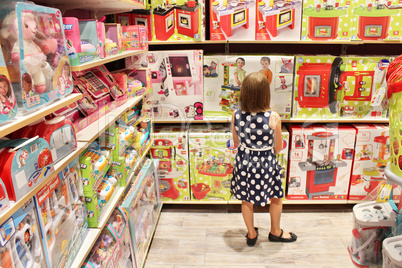 Girl chooses a doll in a toy shop