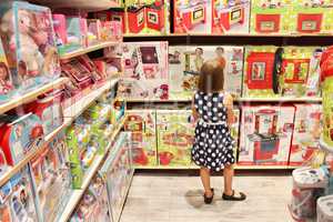 Girl chooses a doll in a toy shop