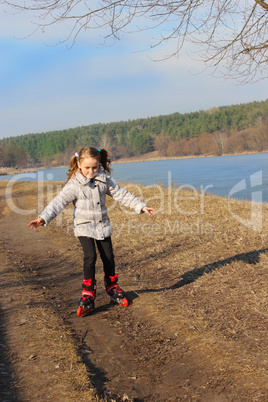 young girl goes in roller skates on the ground