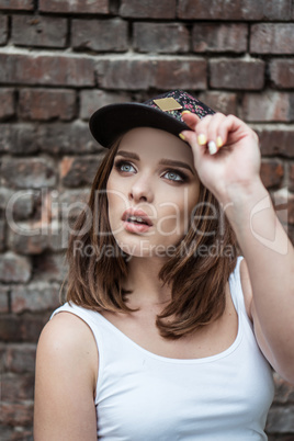 pretty woman on the brick wall wearing sporty hat