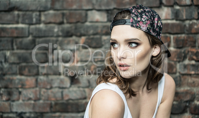 pretty woman on the brick wall wearing sporty hat