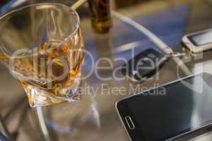 Glass of alcoholic drink and car key, on the table, light background