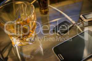 Glass of alcoholic drink and car key, on the table, light background