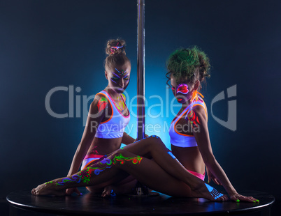 Sexy female dancers sitting together near pole