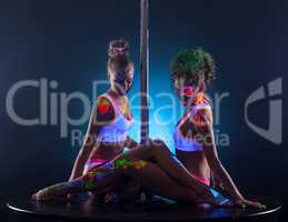 Sexy female dancers sitting together near pole