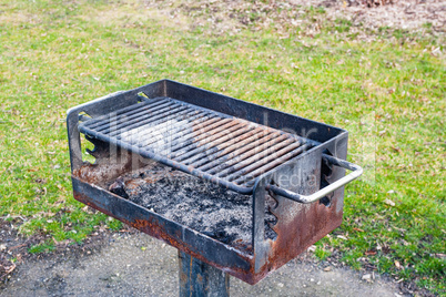 Dirty rusted barbecue grill near grass.