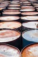Tops of many wet rusted storage drums.