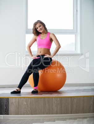 At gym. Pretty girl posing sitting on fitness ball