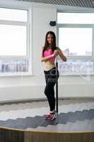 In fitness room. Pretty brunette posing near pylon