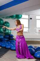 In gym. Beautiful belly dancer posing at camera