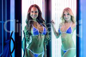 Pretty smiling girls posing in tanning booth