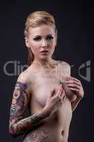Beautiful tattooed model posing nude at camera