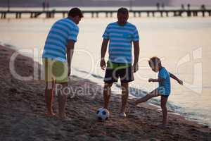 Grandfather, Father and Son Kicking Ball on Beach