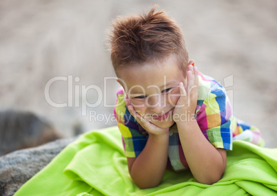 Boy with Head in Hands on Green Beach Blanket