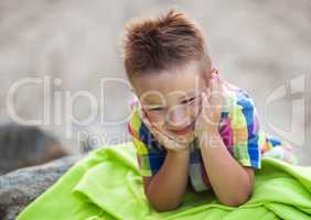 Boy with Head in Hands on Green Beach Blanket