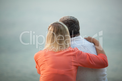 Couple with Arms Around Each Other Admiring Sunset