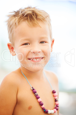 Young Blond Boy Wearing Beaded Necklace on Beach