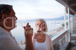 Couple Drinking Red Wine on Balcony of Beach Hotel