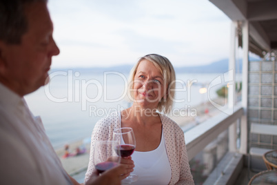 Senior woman drinking wine with husband on balcony