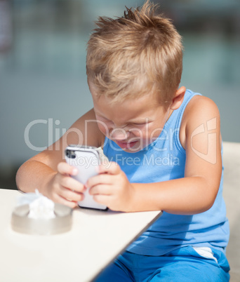 Young boy peering closely at a mobile phone