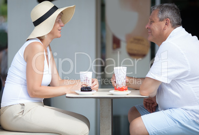 Side view of two smiling elderly people in outdoor cafe