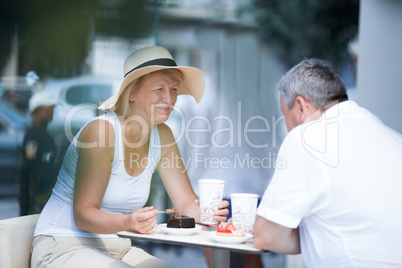 Smiling elderly woman eating in cafe with her husband