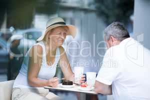 Smiling elderly woman eating in cafe with her husband